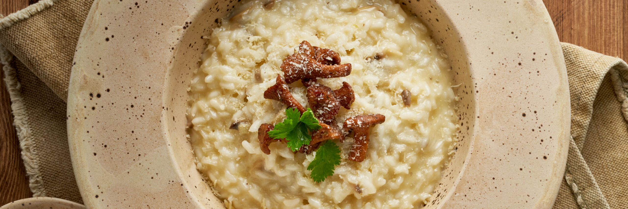 Risoto with chanterelle mushrooms in large plate. Long banner with traditional italian dish.